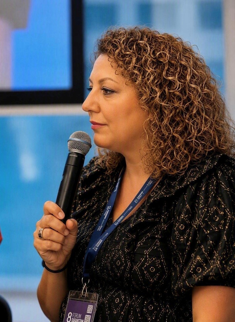 Vasileia Formozi speaking with a microphone at a forum